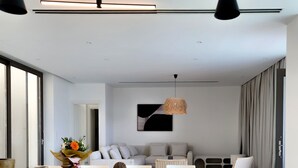 Una sala moderna con comedor, que incluye una mesa grande, sillas blancas y un sofá.