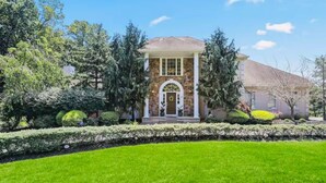 A two-story house with a stone facade, a front porch, and a well-maintained lawn.