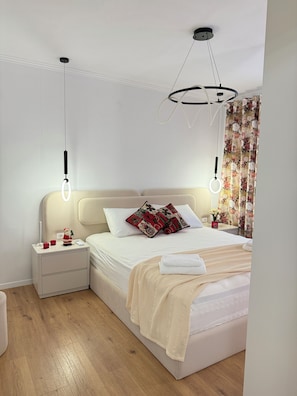 Un dormitorio moderno con cama, mesitas de noche y una lámpara en el techo.