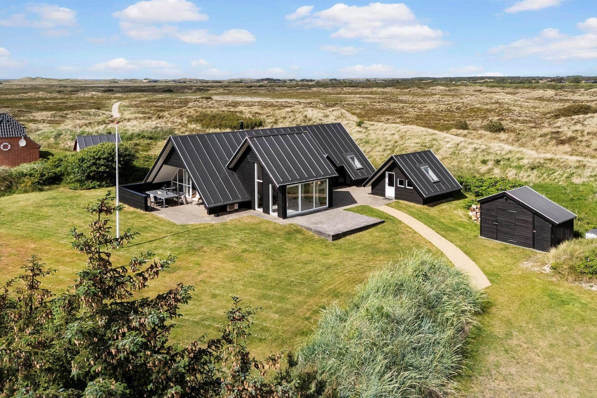 A modern house with a large patio, a garage, and a view of the surrounding landscape.