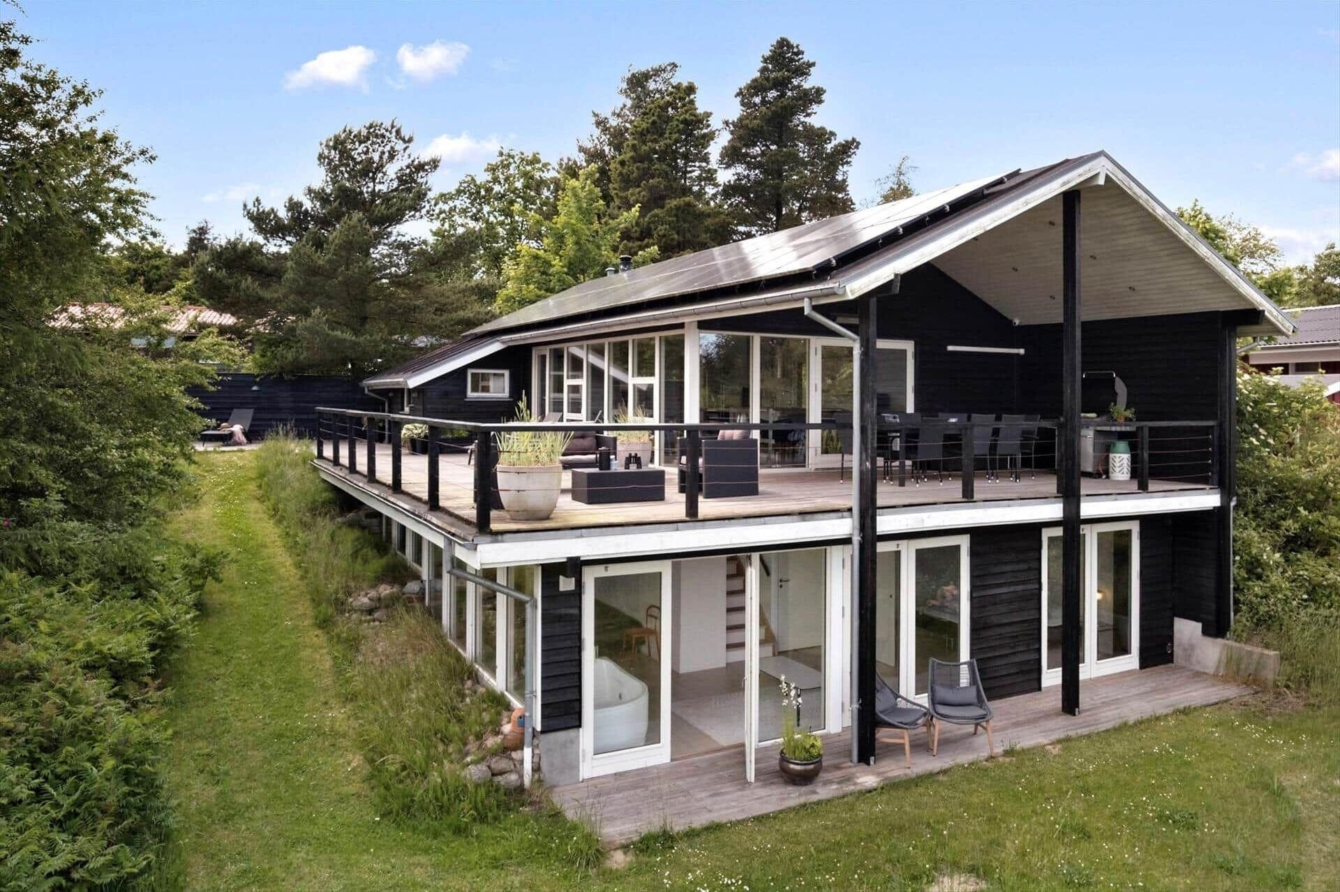 Ein modernes Haus mit einer großen Terrasse, Glastüren und einem Garten.