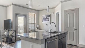 Una cocina moderna con una isla central, electrodomésticos de acero inoxidable y un área de comedor con mesa y sillas.