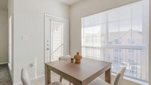 Ein Essbereich mit Tisch, Stühlen und einem Fenster mit Jalousien.