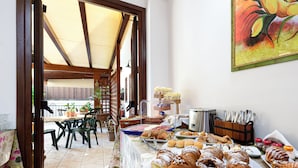 Een ontbijtbuffet met gebak, een koffiehoek en een eetgedeelte met stoelen en tafels.
