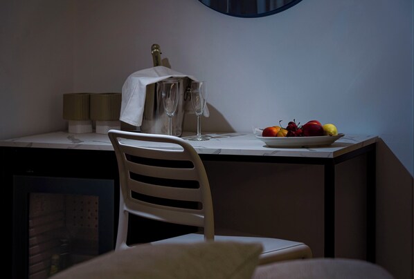 Een eetruimte met een witte stoel, een tafel met een fruitschaal en een lamp.