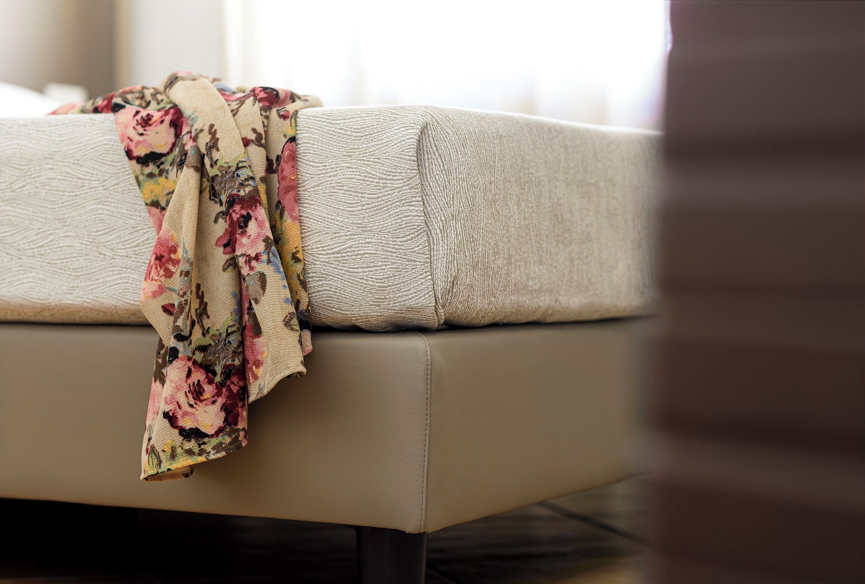 A beige sofa with a floral throw blanket.