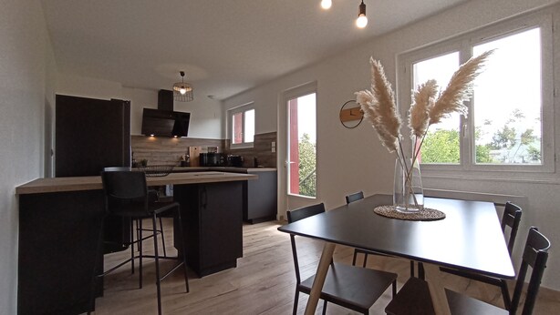 Une cuisine moderne dotée d’un îlot central, de planchers en bois et de grandes fenêtres.