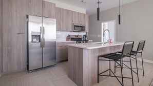 A modern kitchen with a central island, stainless steel appliances, and a minimalist design. - Landing | Chic 3BD in Fountain Heights (Birmingham)