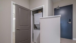 A hallway with a closed door, a washing machine, and a refrigerator. - Landing | Chic 3BD in Fountain Heights (Birmingham)
