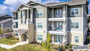 A multi-story residential building with a stone facade, multiple balconies, and a well-maintained lawn. - Landing | Beautiful 1BD, Clubhouse, Pool (San Antonio)