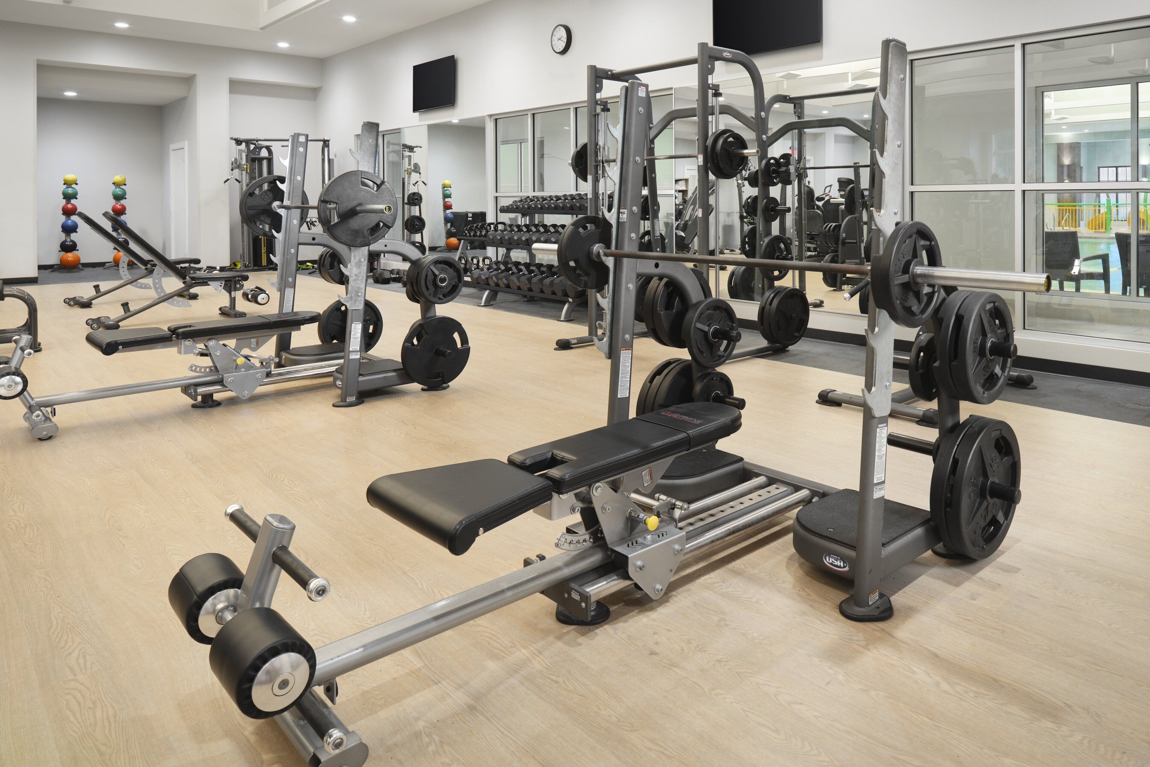 Un gimnasio con diverso equipo de levantamiento de pesas, incluyendo bancos y mancuernas.