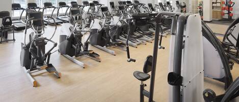 A gym with multiple treadmills, elliptical machines, and weight machines.