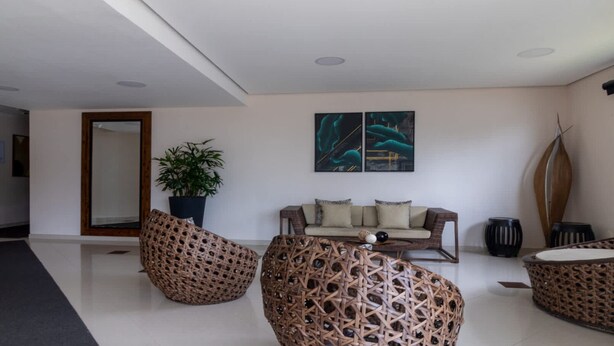 A modern interior with a sofa, two wicker chairs, a coffee table, a potted plant, and abstract wall art.