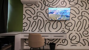 A modern office space with a desk, chair, and a mounted TV displaying a scenic landscape. - Grandstay Studio 111 (Durrës)