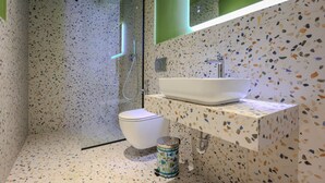 A modern bathroom with a freestanding toilet, a sink with a mirror, and a shower area. - Grandstay Studio 111 (Durrës)