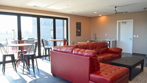 A modern living room with a red leather sofa, a dining area with chairs and a table, and a kitchen in the background. - Landing | Spectacular 1BD, Gym, Game Room (Edwardsville)