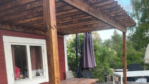 Puinen terassi, jossa on pergola, pöytä ja tuoleja.