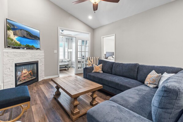 A living room with a fireplace, a sofa, a coffee table, and a television mounted on the wall.