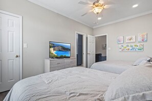 A bedroom with two beds, a TV on a dresser, and artwork on the wall.