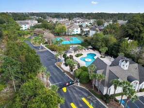 A residential area with a swimming pool, tennis courts, and a parking lot.