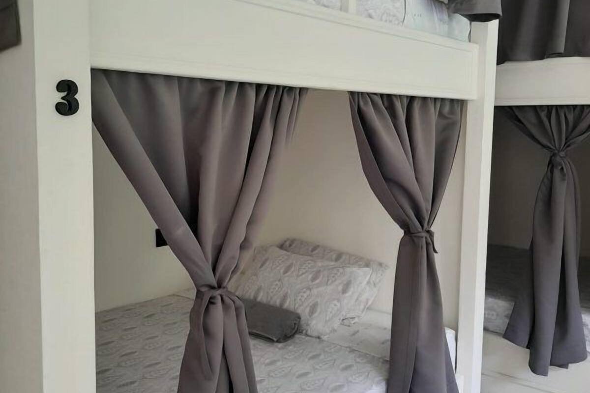 A bunk bed with grey curtains tied at the corners, a white headboard, and a number '3' on the wall.