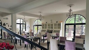 Un comedor amplio con techos altos, ventanas grandes y elegantes candelabros.