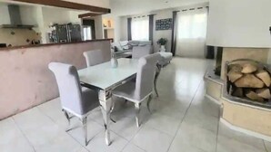 A spacious living area with a dining table and chairs, a kitchen area with modern appliances, and a fireplace.
