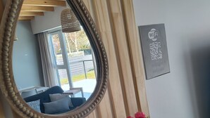 A room with a wooden slat wall, a mirror, a vase with pink and white flowers, a small table with a picture, and a Wi-Fi sign.