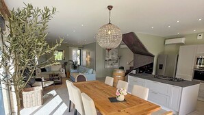A modern kitchen with white cabinets, a central island, and a dining area with a wooden table and chairs.