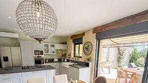 A modern kitchen with white cabinets, a central island, and a chandelier.