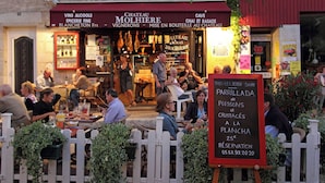 A restaurant with outdoor seating, a signboard advertising a special offer, and a view of the street.
