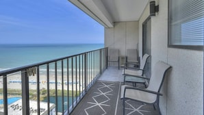 A balcony with a view of the ocean, a patterned floor, and two chairs.