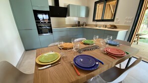 Une cuisine moderne avec des meubles de couleur bleu clair, une table à manger en bois agrémentée d’assiettes et de couverts colorés, et un four encastré.