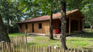 Une cabane en bois dotée d’un porche, entourée d’une clôture en bois et d’arbres.