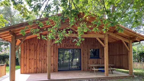 Une cabane en bois dotée d’un patio couvert, d’une porte-fenêtre coulissante et d’une table de pique-nique.