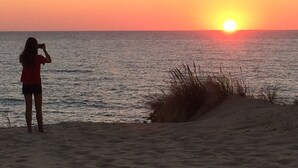 Une personne prend une photo du coucher de soleil sur l’océan.