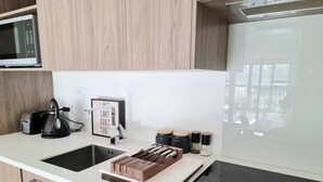 A modern kitchen with a microwave, toaster, and a wooden cutting board with knives. There is a sign on the counter and a window in the background.