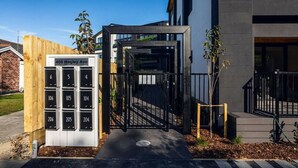 A modern building with a gated entrance and a mailbox with numbered mailboxes.