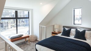 A bedroom with a large bed, a nightstand, a window, and a view of the outside.