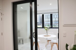 Un interior moderno con una mesa redonda, sillas blancas y un jarrón con flores.