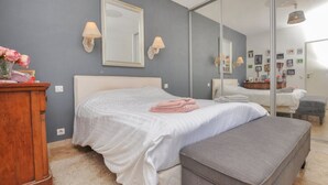 Ein Schlafzimmer mit einem großen Bett, einem Nachttisch, einem Spiegel und einem Kleiderschrank.
