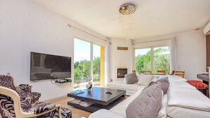 Ein modernes Wohnzimmer mit Flachbildfernseher, einer Sofagarnitur, einem Couchtisch und einem Kamin.