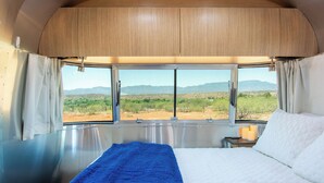 Ein Schlafzimmer mit einem großen Bett, Blick auf eine Wüstenlandschaft und einer Holzbalkendecke.