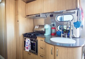 Une cuisine de taille réduite équipée d’une cuisinière, d’un four, d’un four à micro-ondes et d’un évier.