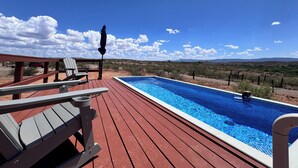 Eine Holzterrasse mit Schwimmbecken, Stuhl und Tisch.