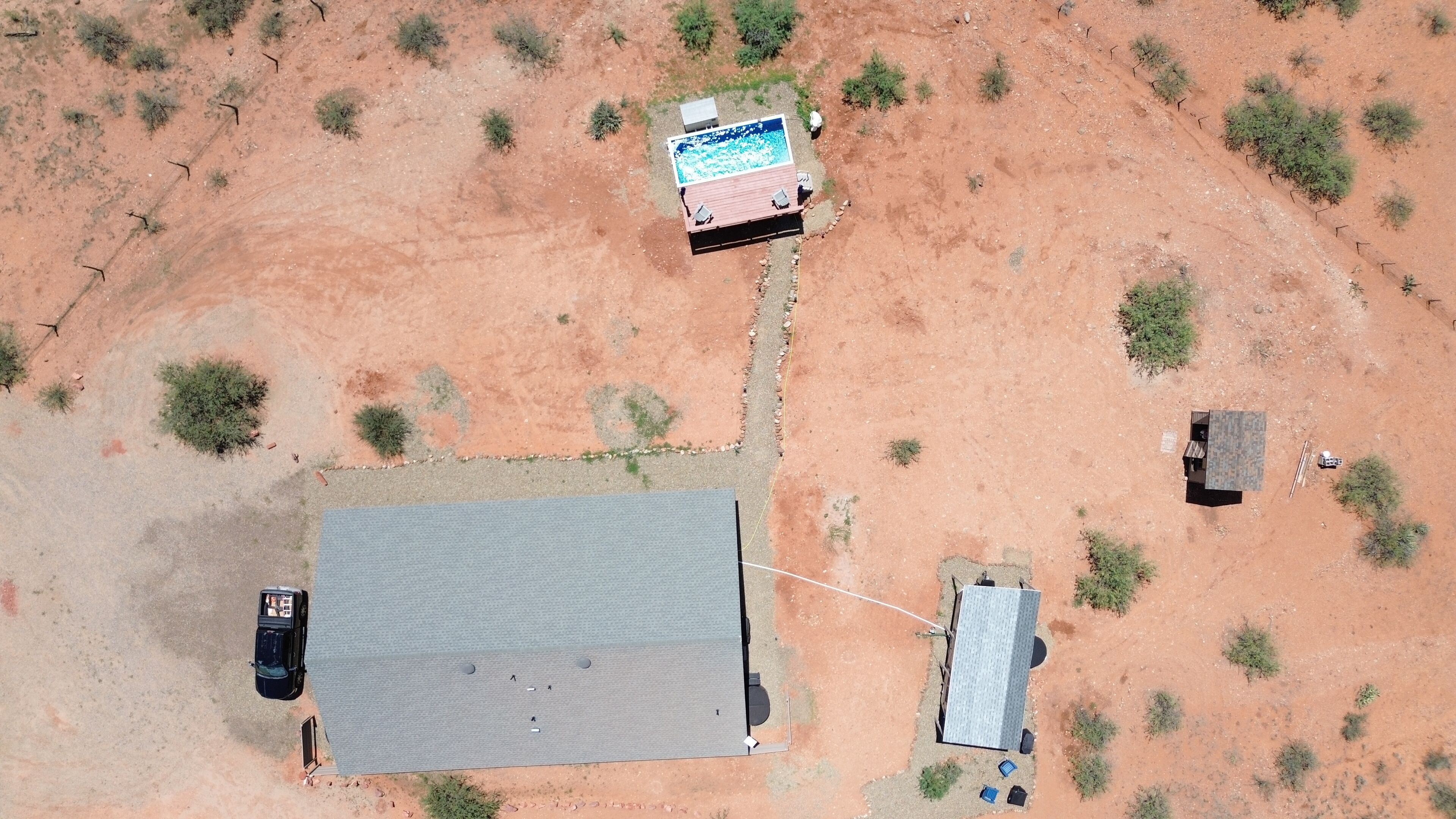An aerial view of a property with a large building, a swimming pool, and a small adjacent structure.