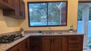A kitchen with granite countertops, a stainless steel sink, and wooden cabinets. - Soothing 4-bedroom country house in Piedra Blanca (Piedra Blanca)