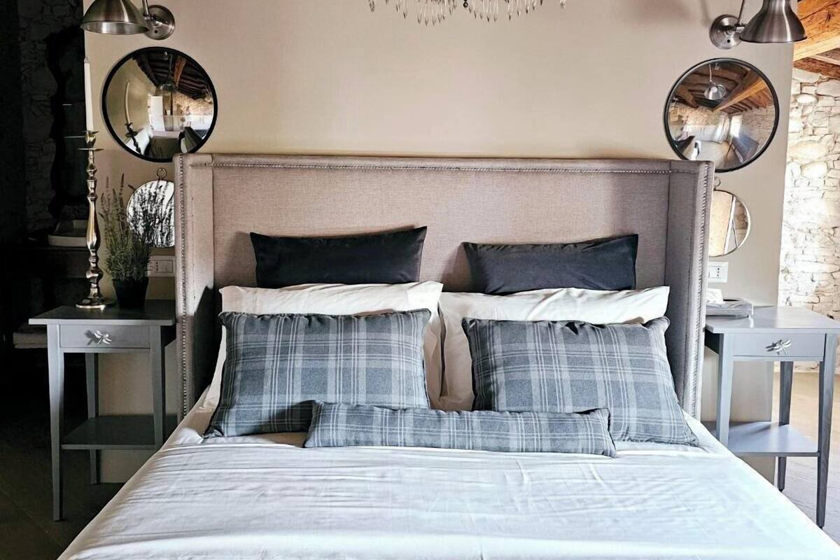 Un dormitorio con una cama grande, dos mesitas de noche, una araña y un espejo en la pared.