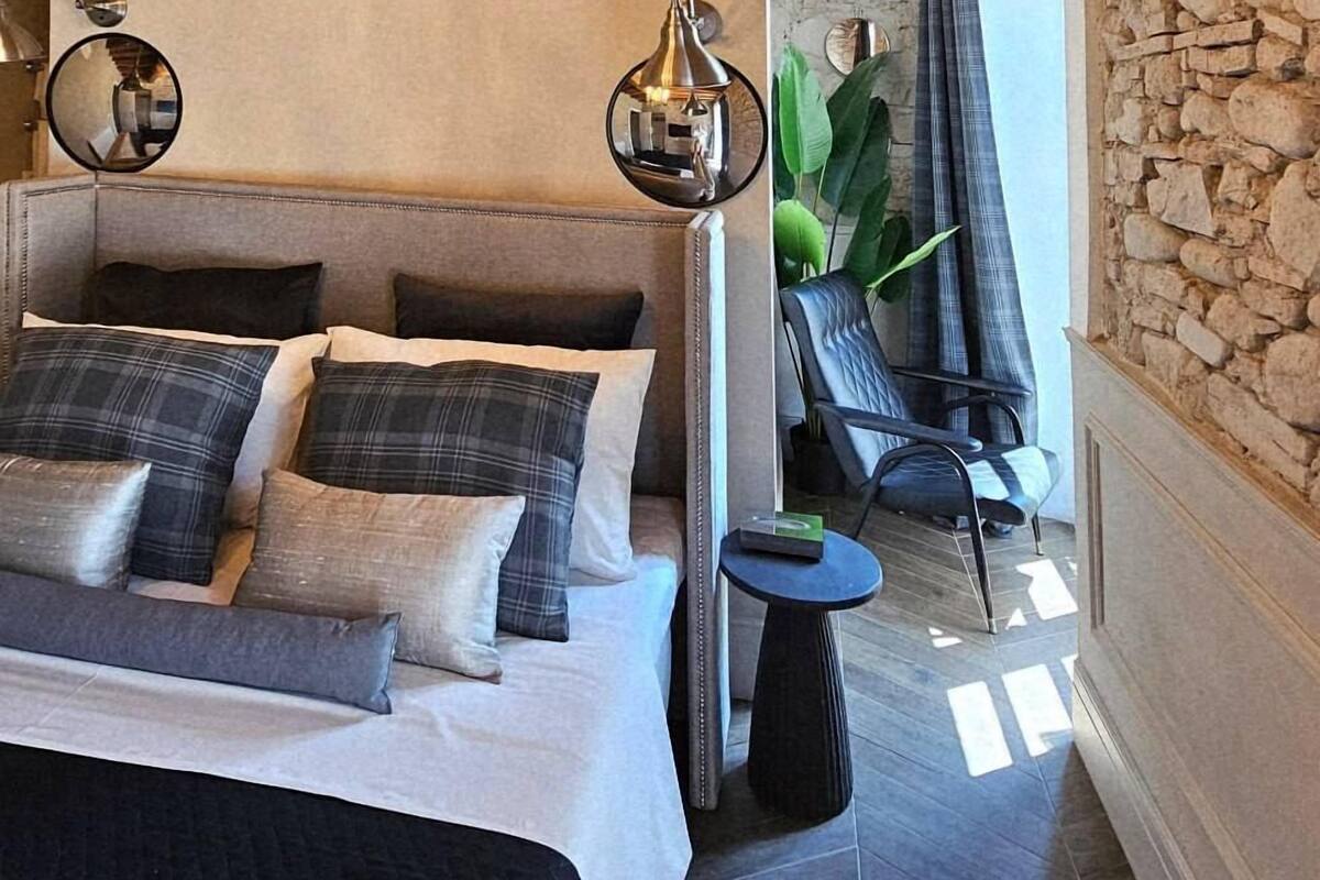 Un dormitorio moderno con una cama grande, una araña y una pared de piedra.