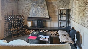 Un interior rústico con paredes de ladrillo visto, una chimenea de piedra, una estantería para vinos y una zona de estar acogedora con chimenea.